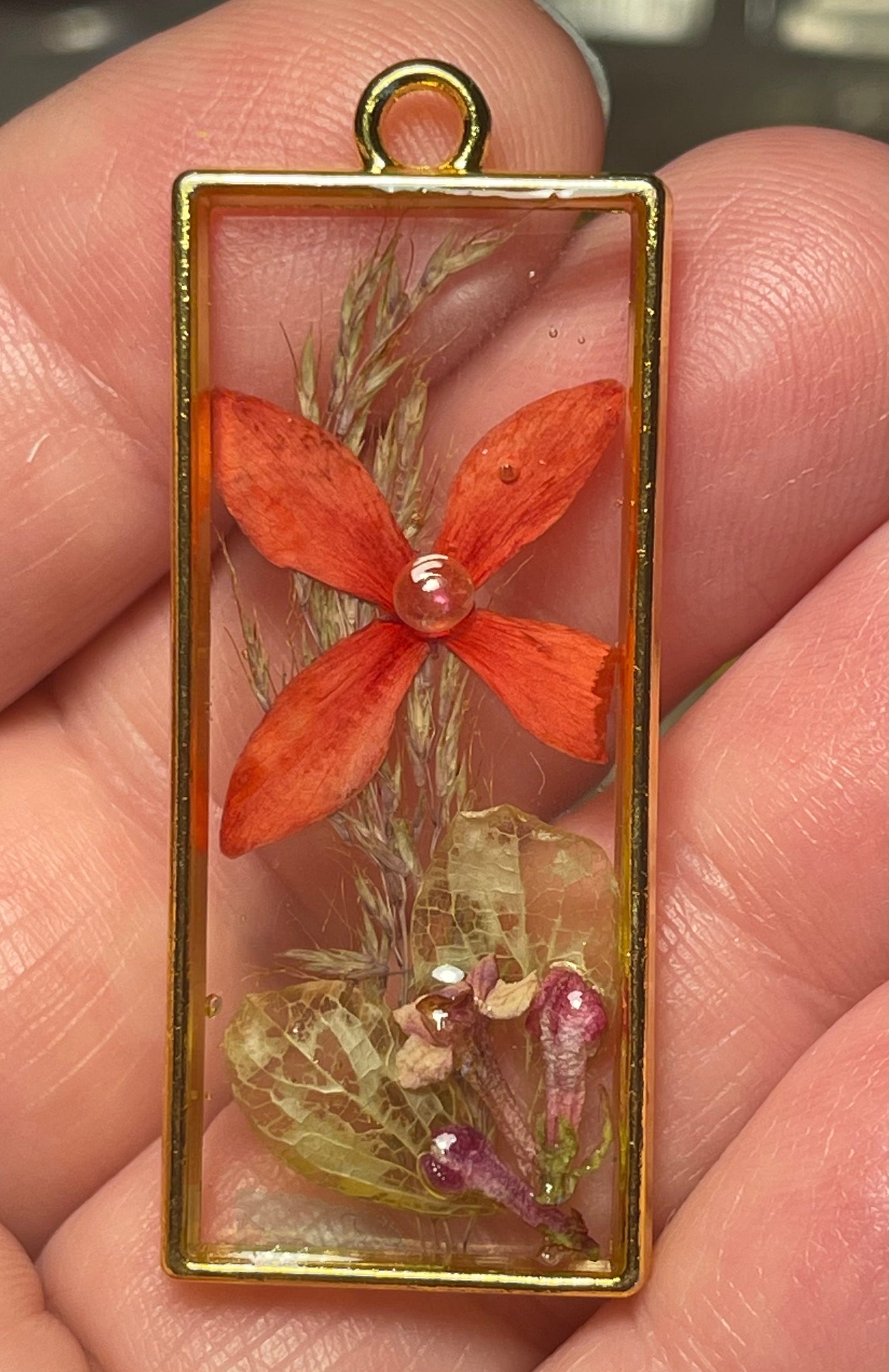 Rectangular resin gold bezel with dried red flower and green leaves
